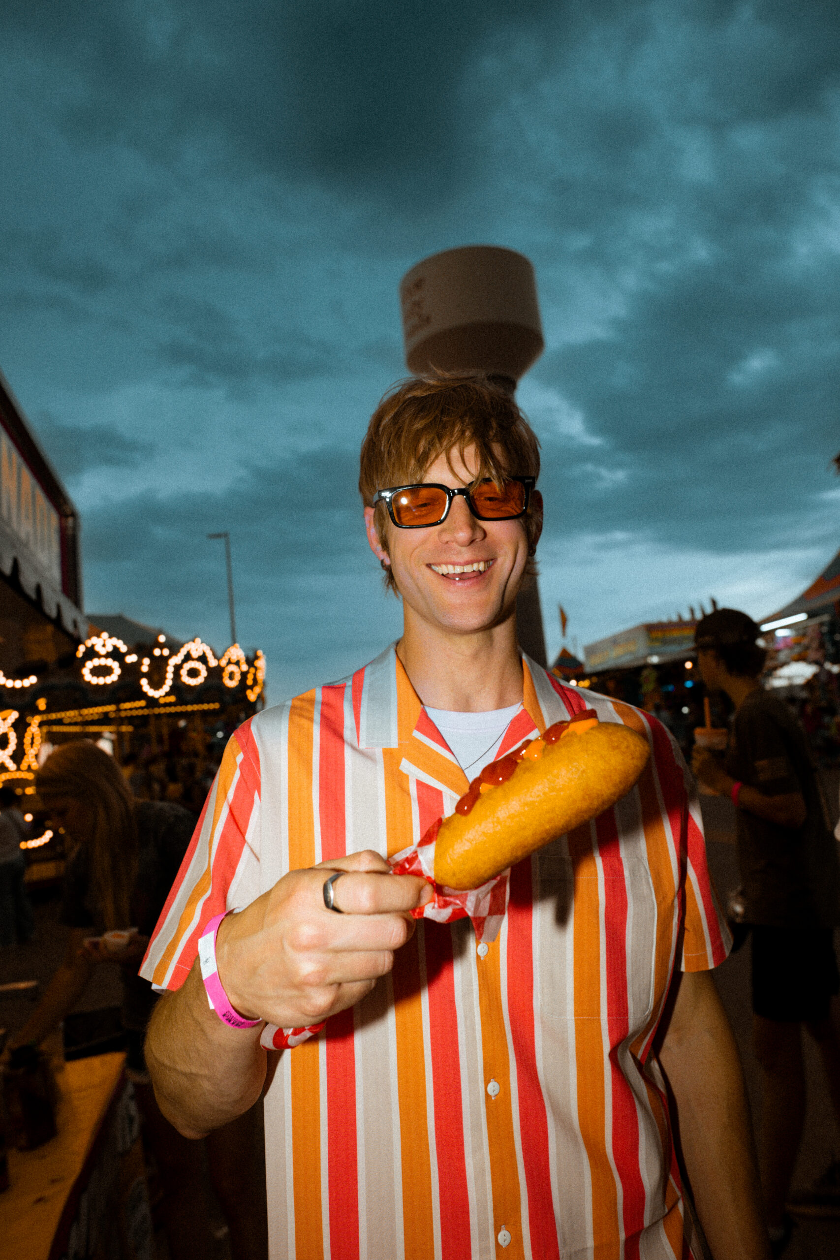 Retro-styled fairgoer holding a corn dog on the midway