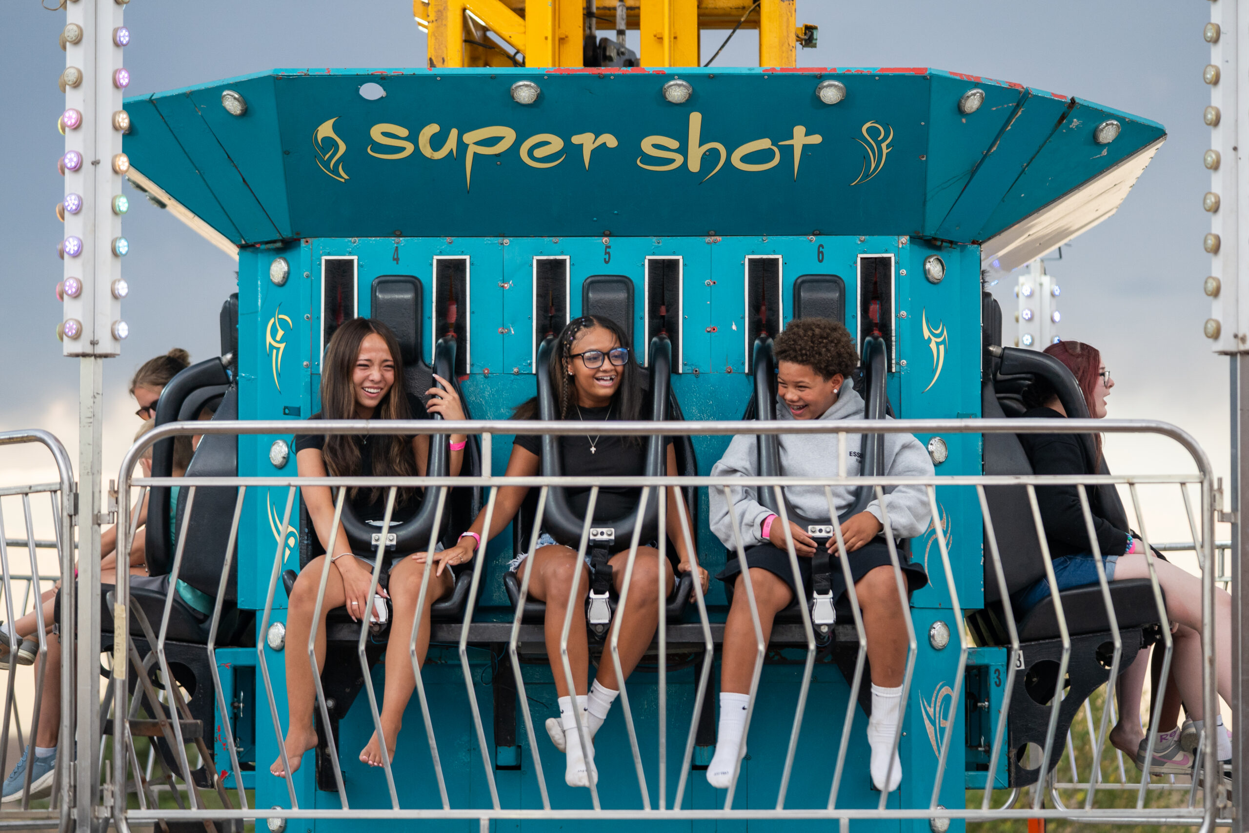 Friends laughing as they prepare to ride the Super Shot at the county fair