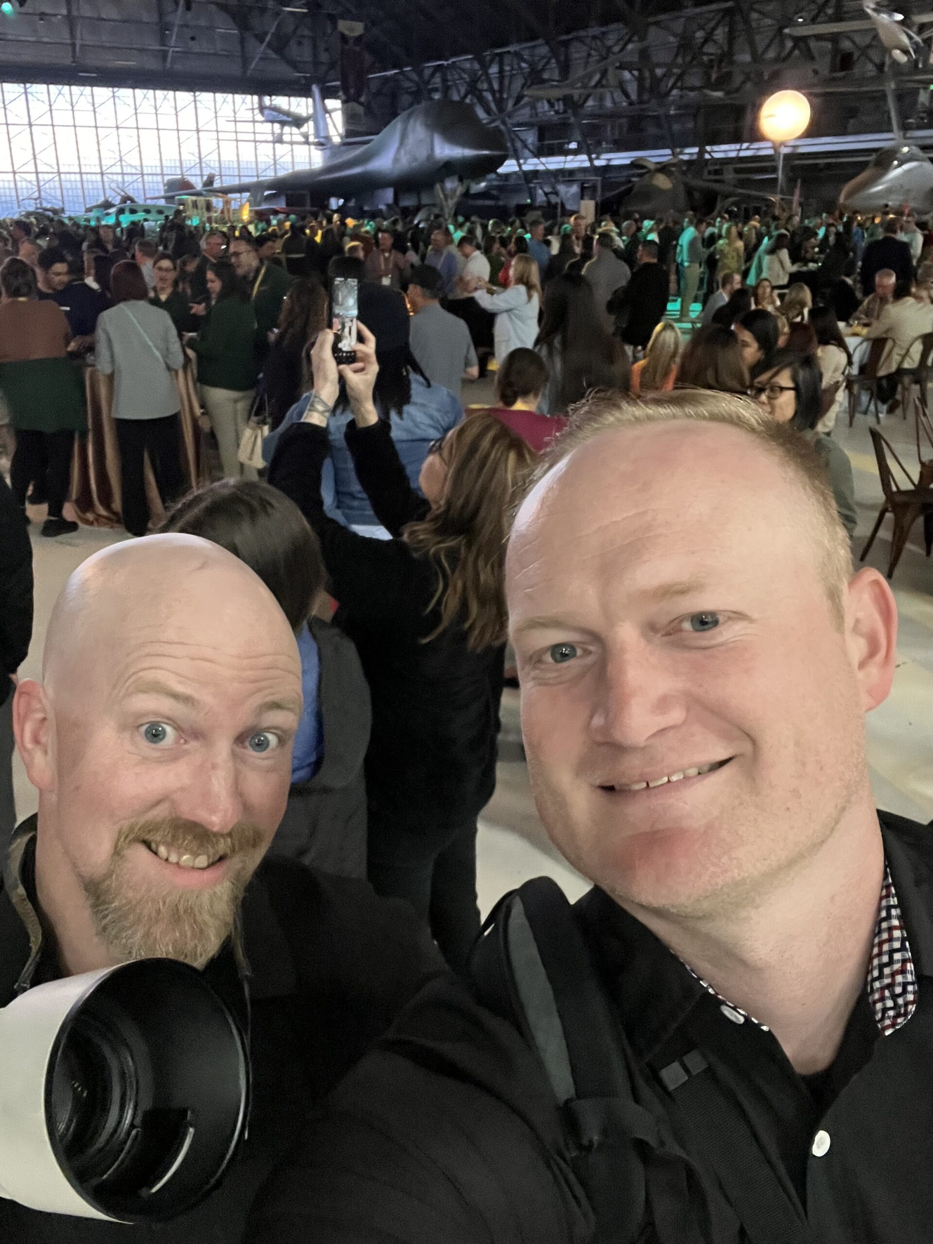 Devin and Charlie working together with cameras at an aircraft hangar event